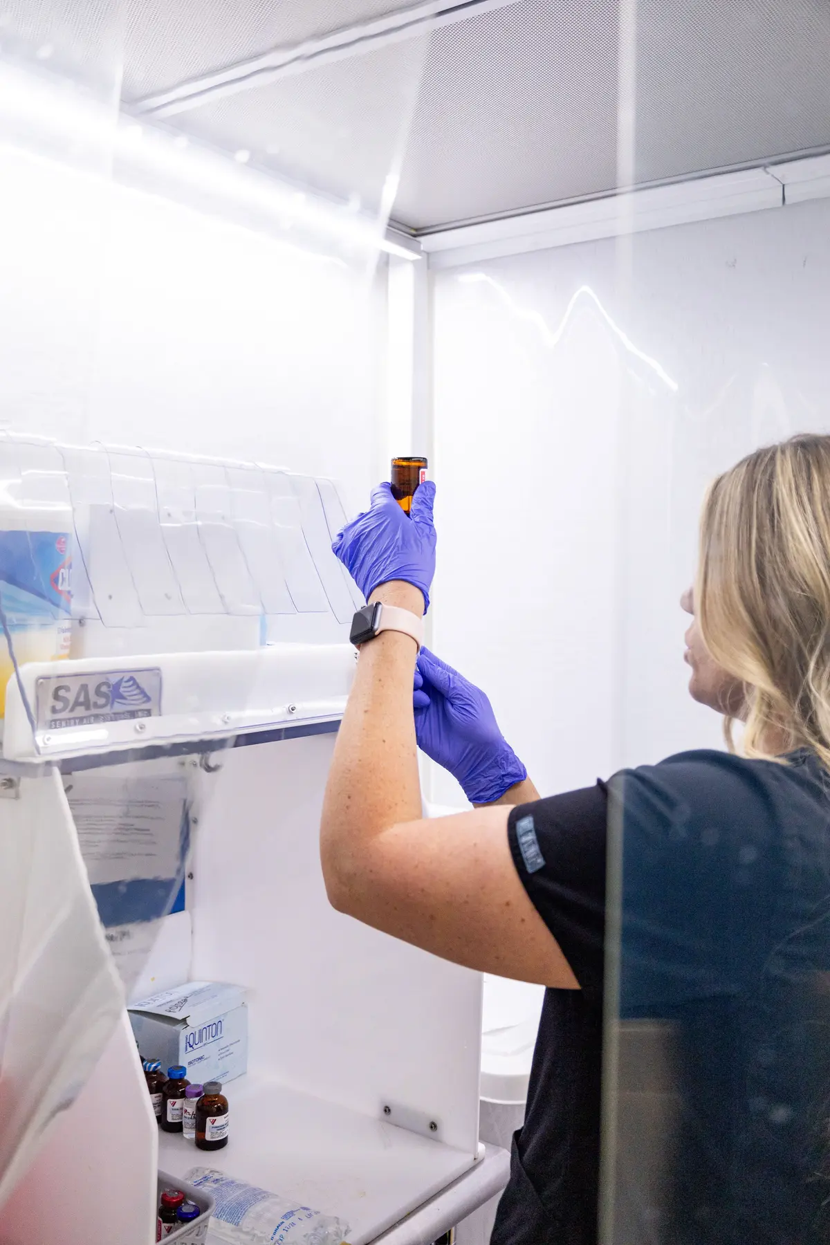 Nascent Health provider inspecting a compounded vial under a sterile hood