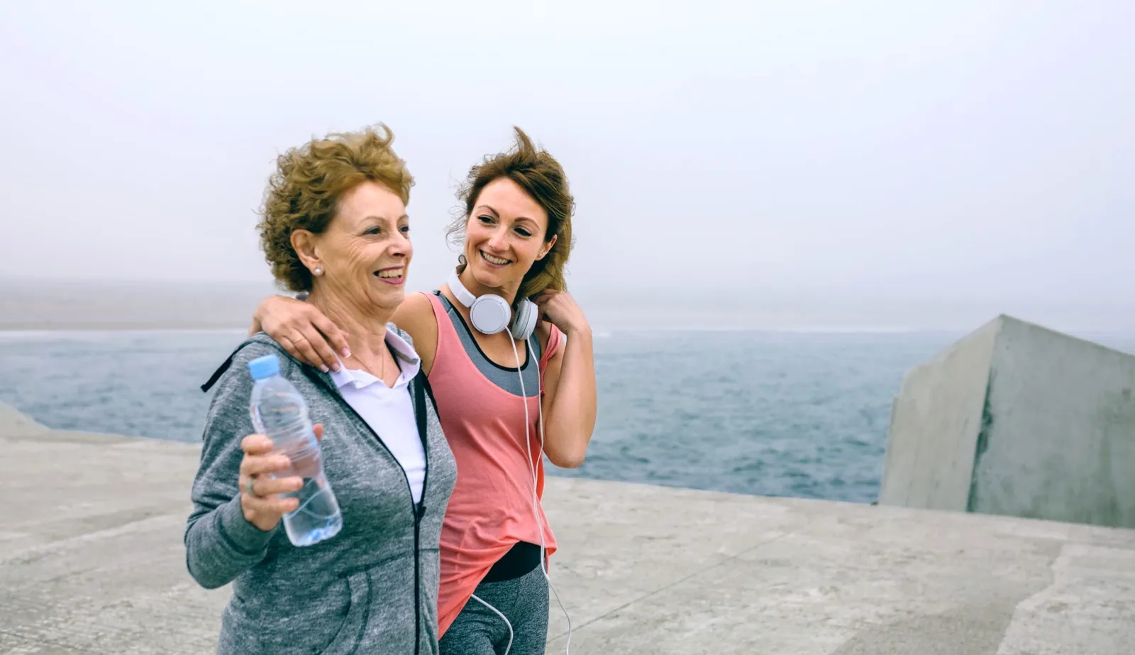 Two women walking together by the water