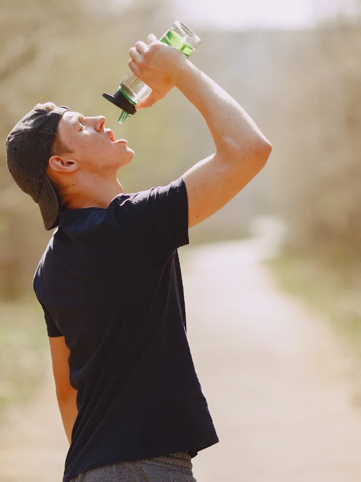 Man drinking water outdoors after exercise