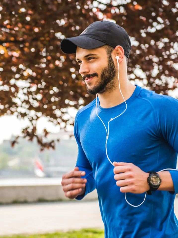 Man jogging through a park with headphones
